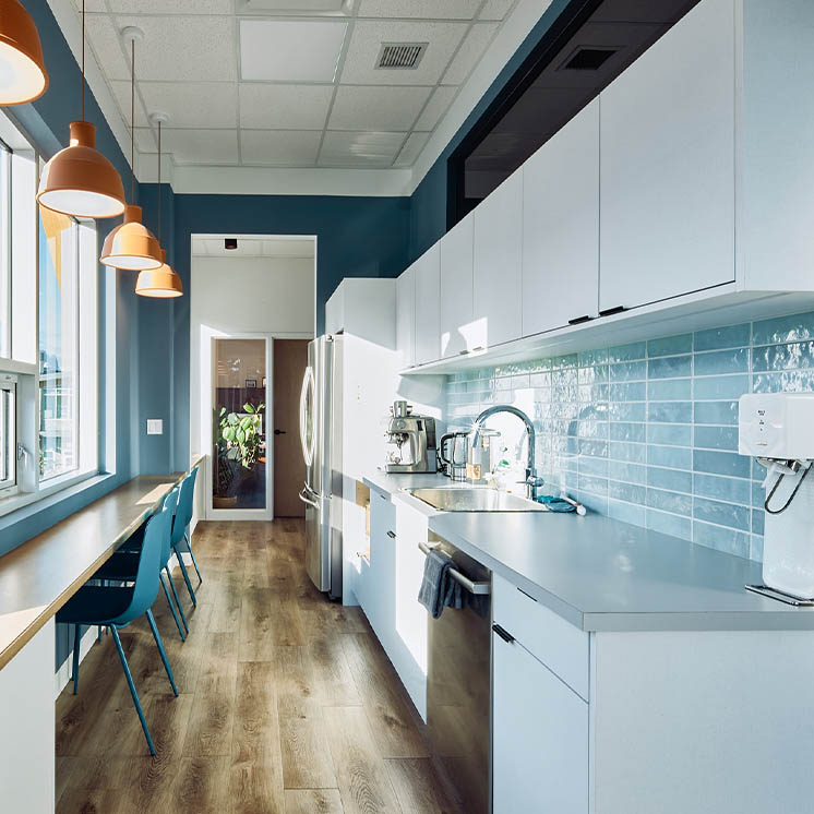 Empty staff kitechen with white cabinets and blue tile backsplash Empty staff kitechen with white cabinets and blue tile backsplash